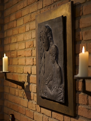 Marienrelief mit Jesuskind in der St. Franziskus Kirche Wersen Reliefdarstellung von Maria mit dem Jesuskind, flankiert von zwei Kerzen in der Kirche St. Franziskus in Wersen